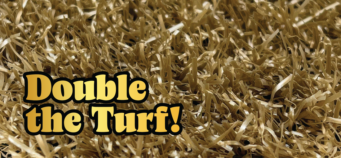 A close-up view of artificial grass fibers with the bold text “Double the Turf!” in yellow and black letters overlaid on the left side of the image.
