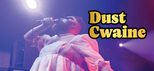 A performer in a white dress and pearl necklace sings passionately into a microphone on stage, with dramatic lighting and the text Dust Cwaine in bold yellow letters beside them.